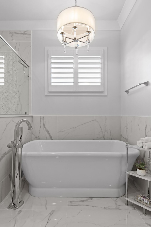 bathroom featuring a bathing tub, tile walls, and an inviting chandelier