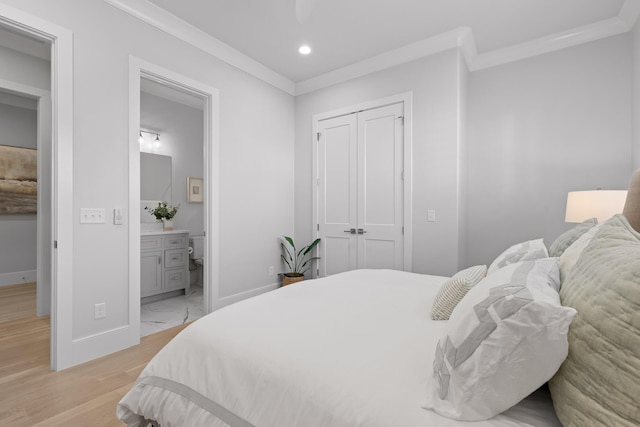 bedroom with ensuite bathroom, ornamental molding, a closet, and light wood-type flooring