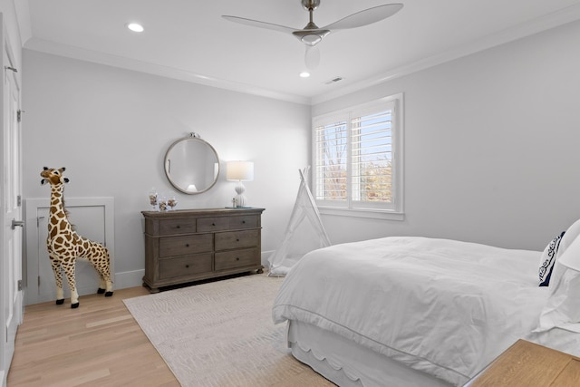 bedroom with ornamental molding, ceiling fan, and light hardwood / wood-style flooring