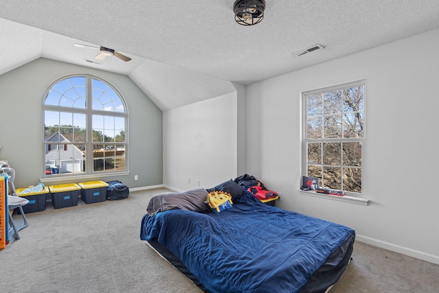 carpeted bedroom featuring ceiling fan, vaulted ceiling, and a textured ceiling