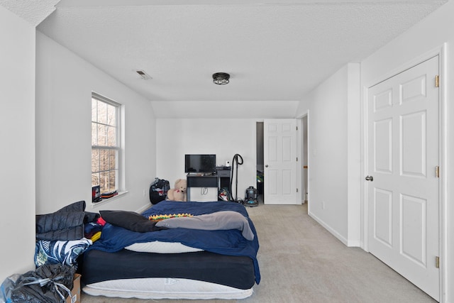 bedroom with light colored carpet and a textured ceiling