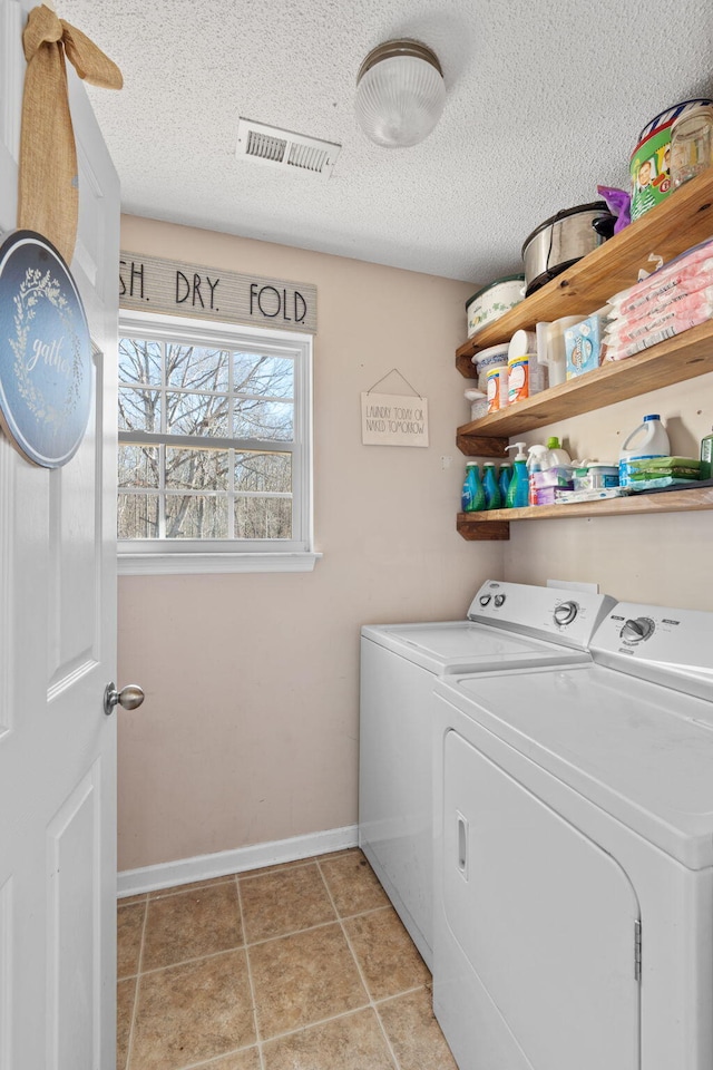 washroom featuring light tile patterned floors, washer and dryer, and a textured ceiling