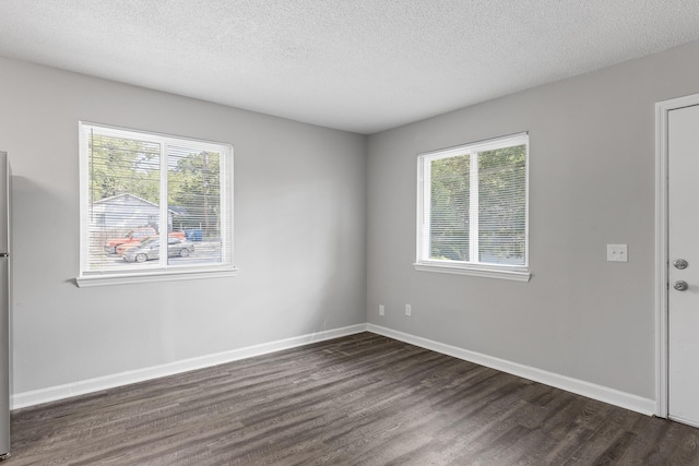 unfurnished room with a wealth of natural light, dark hardwood / wood-style floors, and a textured ceiling