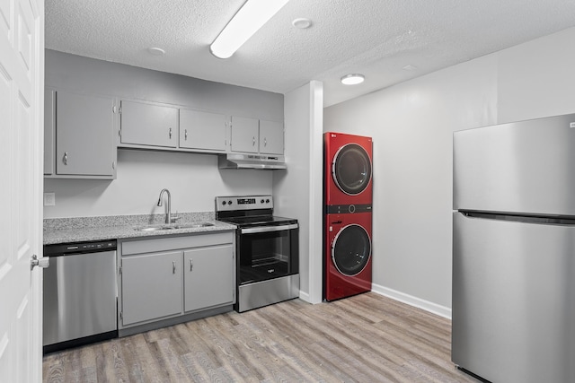 kitchen with stacked washer and dryer, sink, gray cabinetry, a textured ceiling, and appliances with stainless steel finishes