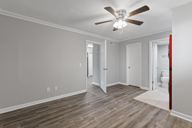 unfurnished bedroom with connected bathroom, a textured ceiling, ornamental molding, hardwood / wood-style flooring, and ceiling fan