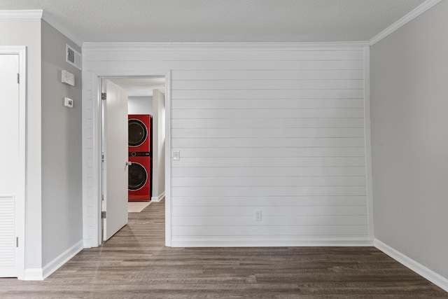 spare room featuring crown molding, stacked washer and clothes dryer, hardwood / wood-style floors, and a textured ceiling