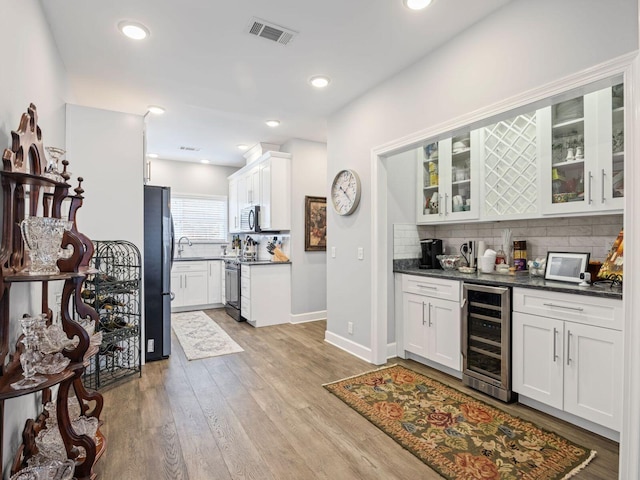 kitchen with white cabinetry, appliances with stainless steel finishes, and beverage cooler