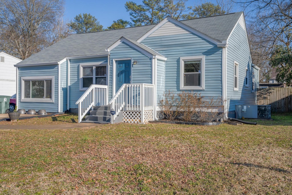 bungalow-style house featuring central AC unit and a front yard