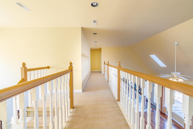 corridor with lofted ceiling with skylight and light carpet