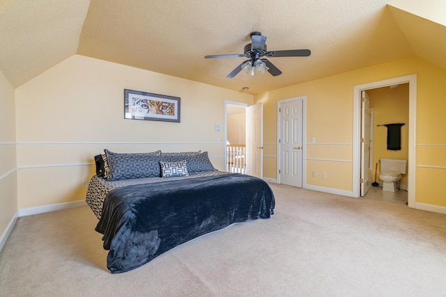 bedroom with ensuite bath, vaulted ceiling, light colored carpet, and a textured ceiling