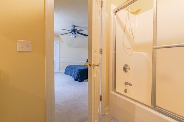 bathroom featuring ceiling fan, combined bath / shower with glass door, lofted ceiling, and a textured ceiling