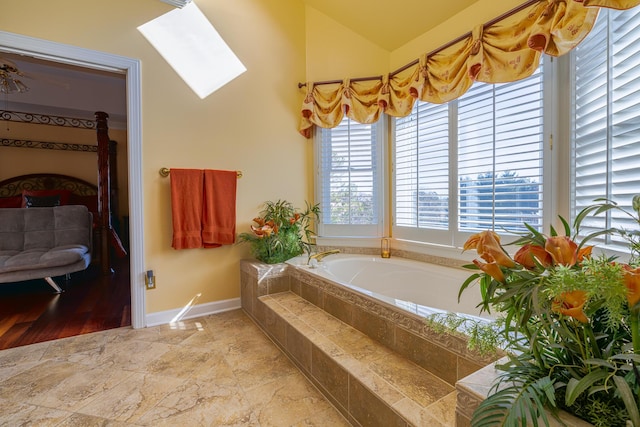 bathroom featuring a relaxing tiled tub and vaulted ceiling with skylight