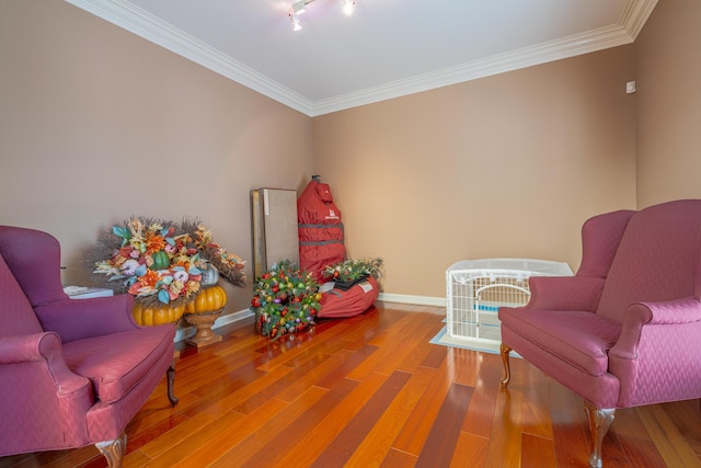 sitting room with hardwood / wood-style flooring, track lighting, and ornamental molding