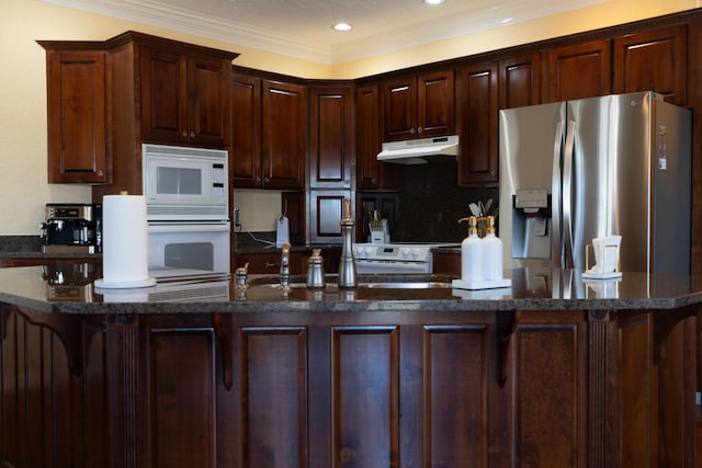 kitchen with white appliances, dark brown cabinetry, decorative backsplash, and dark stone countertops