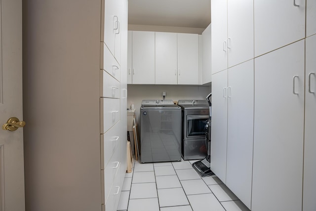 washroom with cabinets, washer and dryer, and light tile patterned flooring