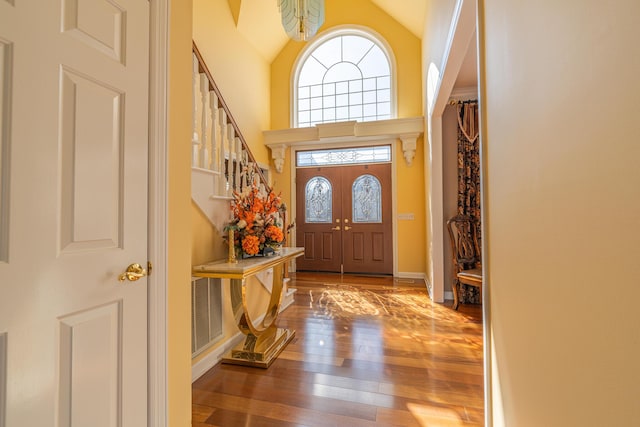 foyer entrance with wood-type flooring and high vaulted ceiling