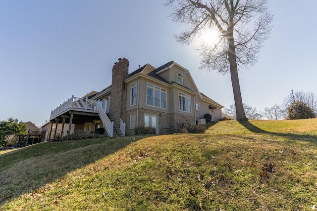 view of side of property with a wooden deck and a lawn