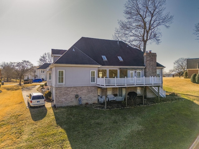 rear view of house with a deck and a lawn