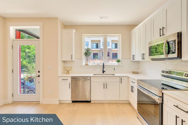 kitchen with white cabinetry, stainless steel appliances, sink, and decorative backsplash