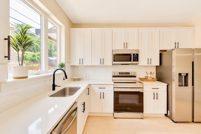 kitchen featuring appliances with stainless steel finishes, sink, white cabinets, and plenty of natural light