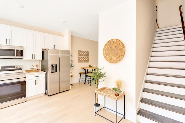 kitchen with tasteful backsplash, light hardwood / wood-style flooring, stainless steel appliances, and white cabinets