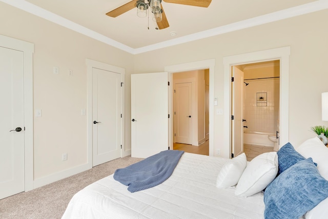 carpeted bedroom with ensuite bathroom, ornamental molding, and ceiling fan