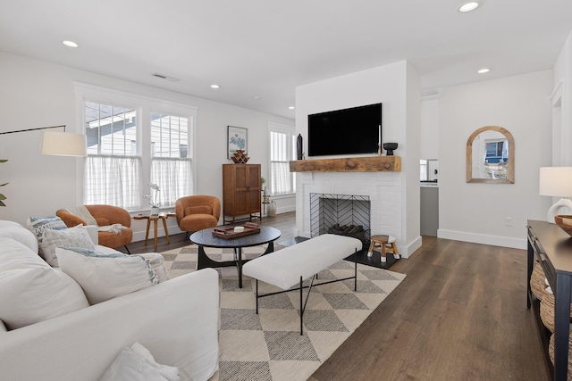 living room featuring a brick fireplace and dark wood-type flooring