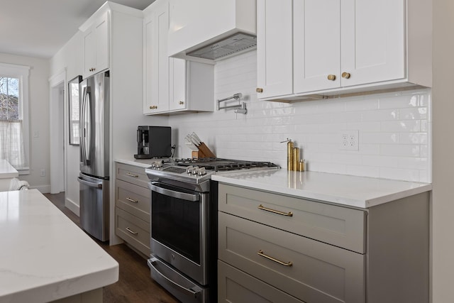 kitchen with appliances with stainless steel finishes, dark hardwood / wood-style floors, white cabinetry, light stone countertops, and custom range hood