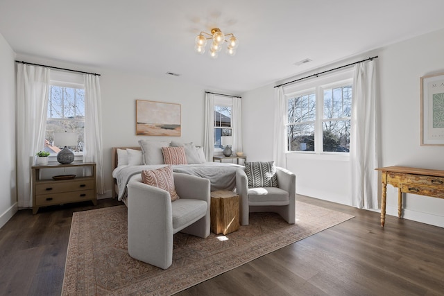 bedroom featuring multiple windows, dark wood-type flooring, and a chandelier