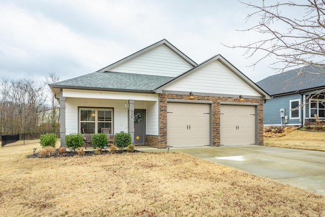 view of front of property with a porch, a garage, and a front lawn