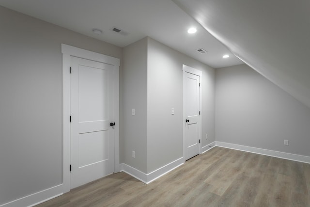 bonus room with vaulted ceiling and light wood-type flooring