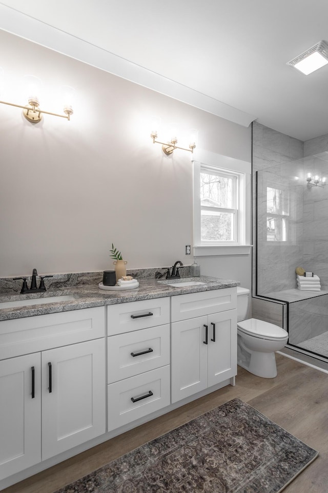 bathroom with vanity, hardwood / wood-style floors, toilet, and tiled shower