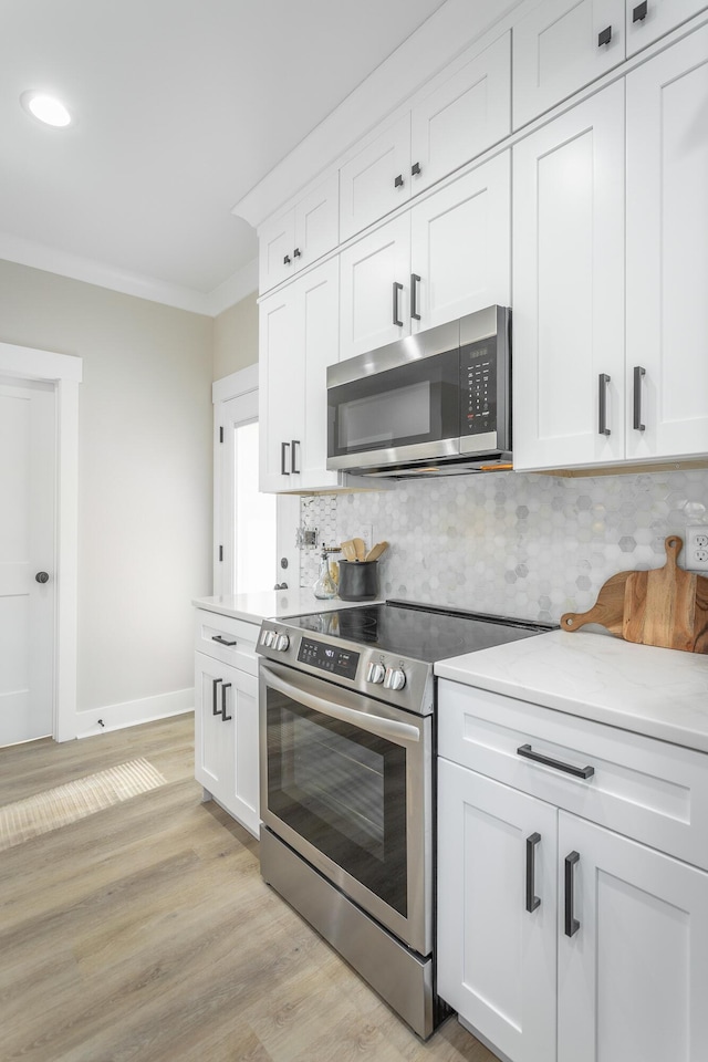 kitchen with backsplash, stainless steel appliances, light hardwood / wood-style flooring, and white cabinets