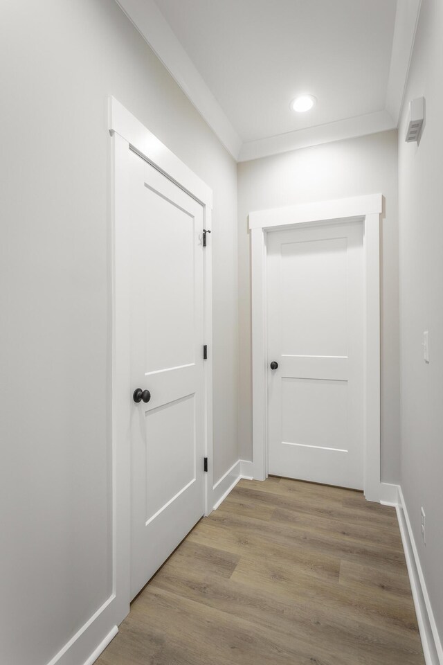 corridor featuring crown molding and light hardwood / wood-style flooring