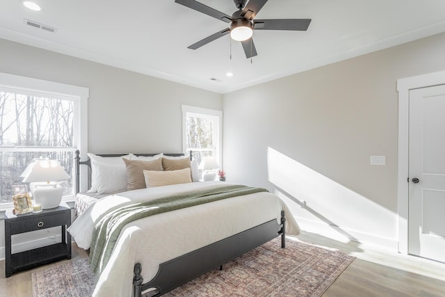 bedroom with multiple windows, hardwood / wood-style flooring, and ceiling fan