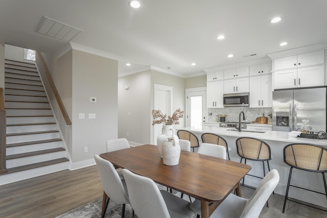 dining room with crown molding, sink, and dark wood-type flooring