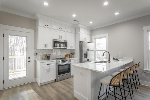 kitchen featuring white cabinetry, sink, stainless steel appliances, and a breakfast bar