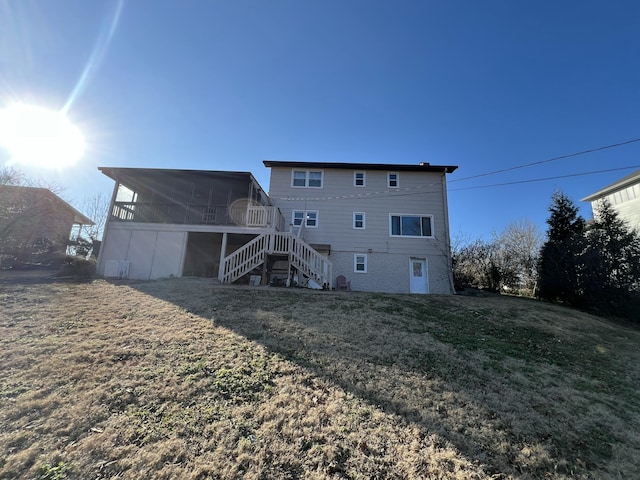 rear view of house featuring a yard, stairway, and a sunroom