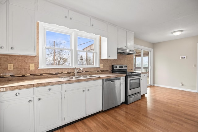 kitchen with stainless steel appliances, white cabinets, a sink, and under cabinet range hood