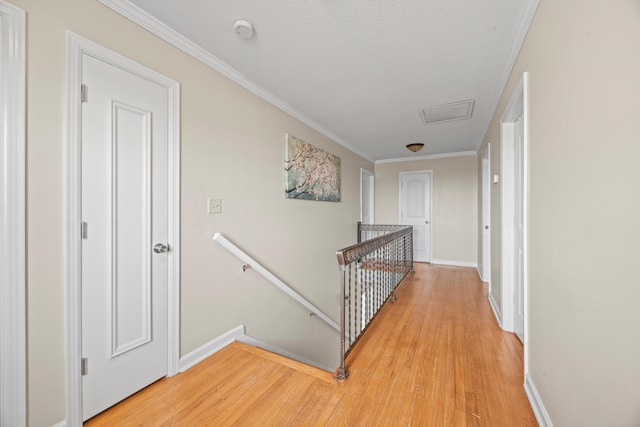 corridor featuring ornamental molding, wood finished floors, and an upstairs landing