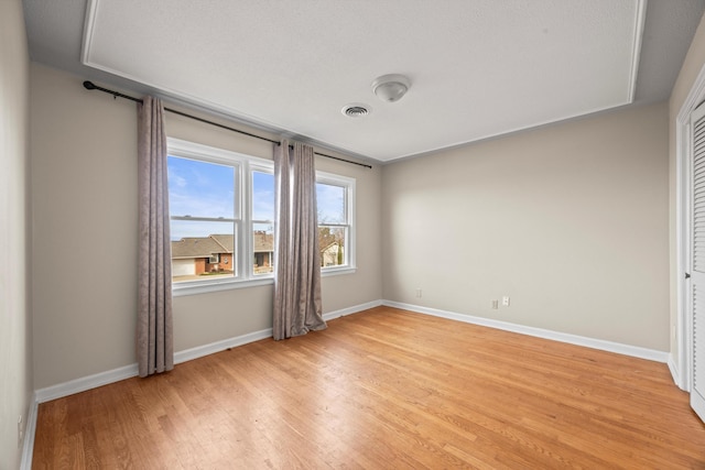 unfurnished room featuring light wood finished floors, baseboards, and visible vents