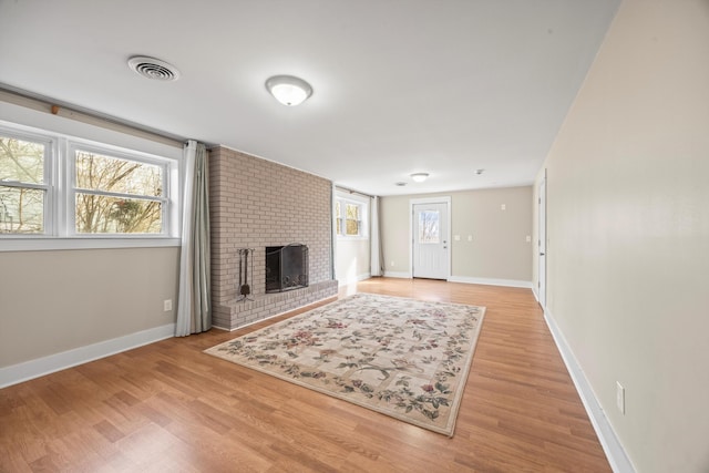 living room with baseboards, a fireplace, visible vents, and wood finished floors