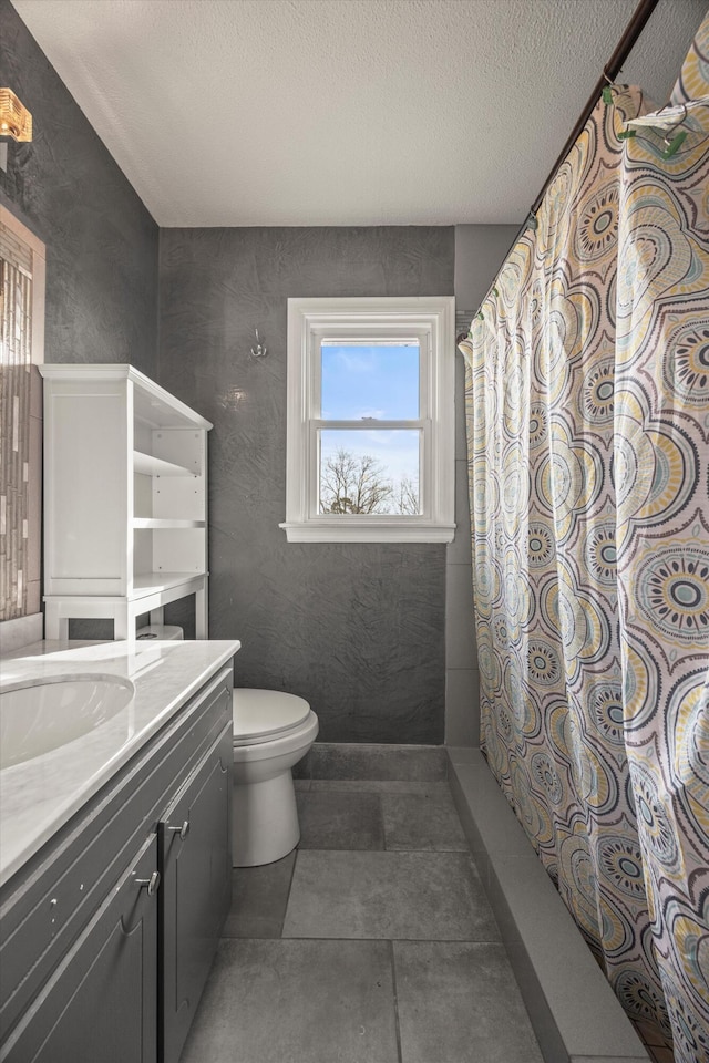 full bathroom with a textured ceiling, curtained shower, toilet, vanity, and tile patterned floors