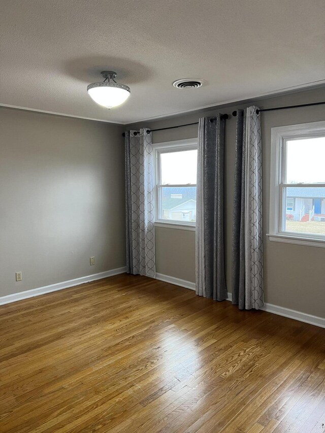 unfurnished room featuring baseboards, visible vents, plenty of natural light, and light wood finished floors