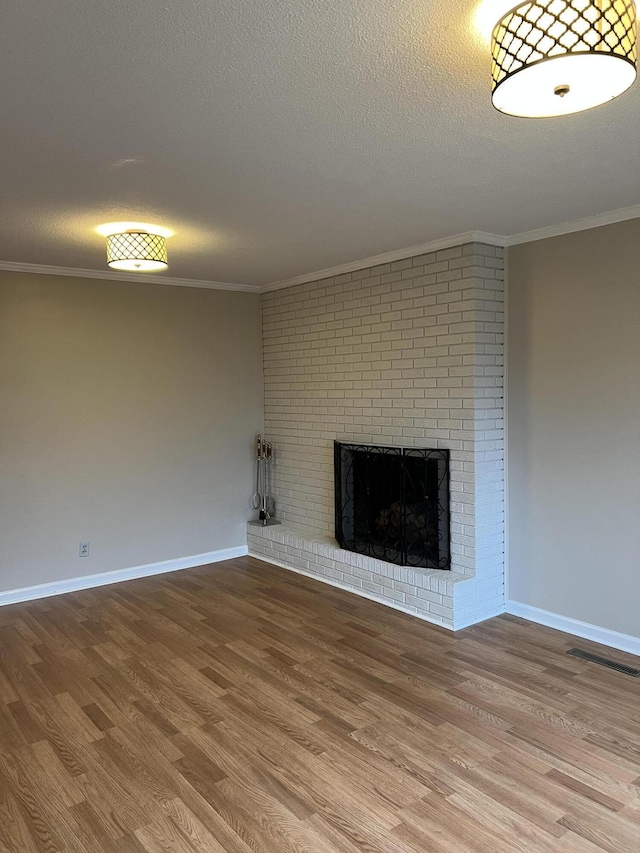 unfurnished living room featuring ornamental molding, a brick fireplace, and wood finished floors