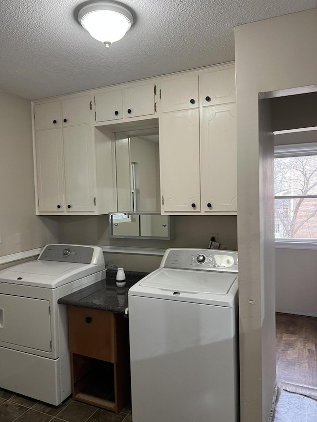 washroom with cabinet space, a textured ceiling, and washing machine and clothes dryer