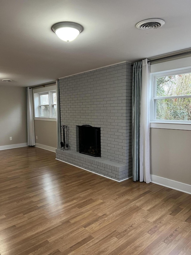 unfurnished living room with light wood-style flooring, a fireplace, visible vents, and baseboards