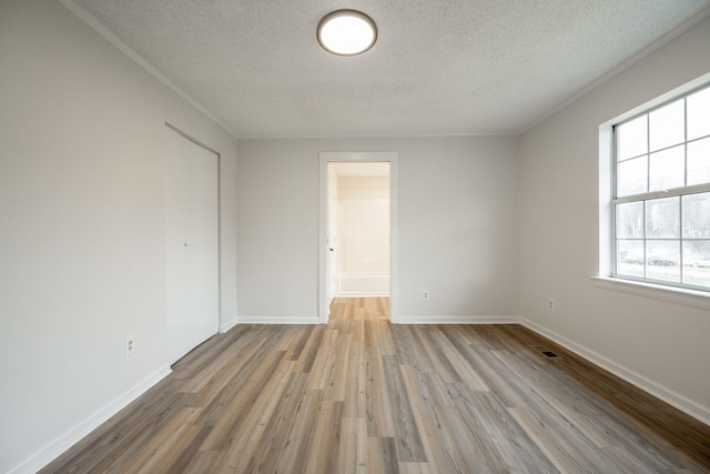 unfurnished room featuring ornamental molding, light hardwood / wood-style flooring, and a textured ceiling