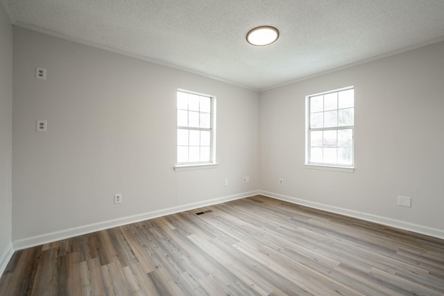 empty room featuring crown molding, plenty of natural light, light hardwood / wood-style flooring, and a textured ceiling