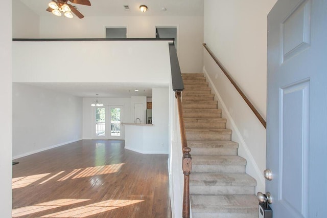 staircase with wood-type flooring and ceiling fan with notable chandelier